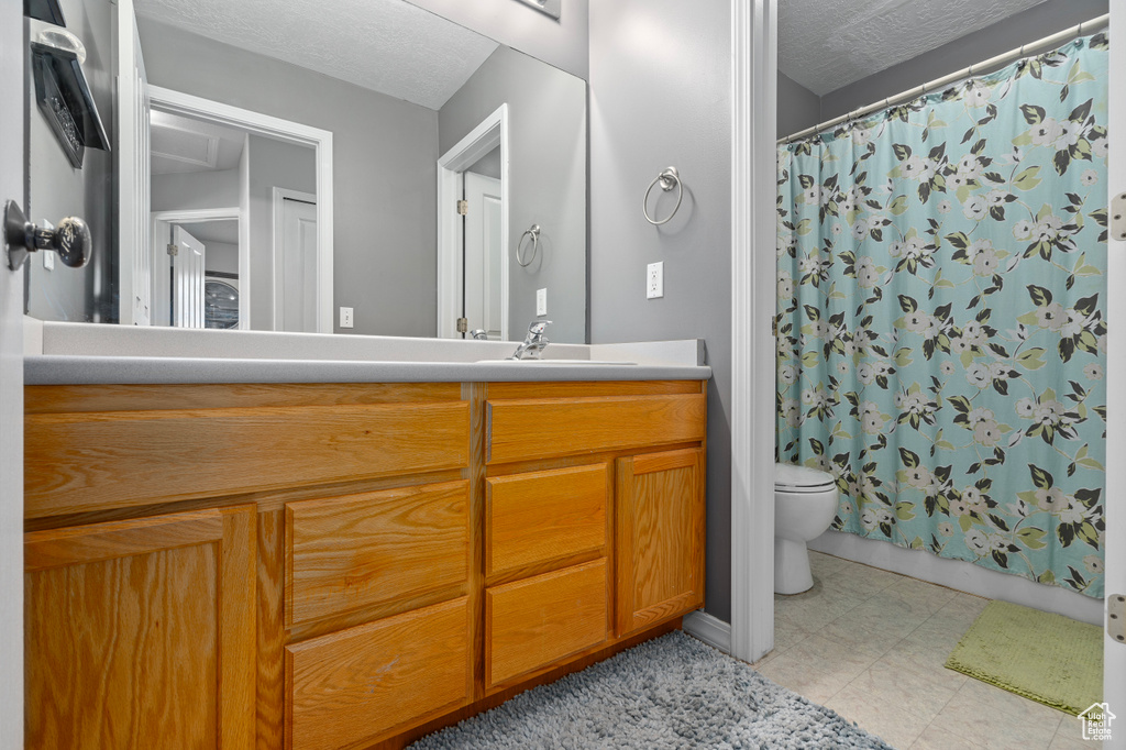 Bathroom with a shower with curtain, vanity, toilet, and a textured ceiling