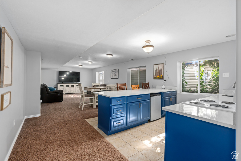 Kitchen with open floor plan, a peninsula, light countertops, stovetop, and blue cabinetry