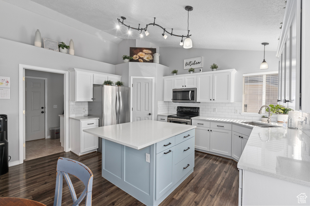 Kitchen with white cabinets, vaulted ceiling, stainless steel appliances, and a sink