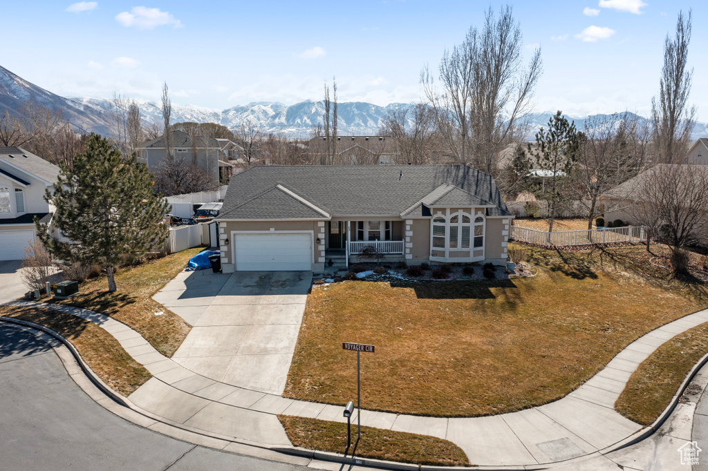 View of front facade with a mountain view, driveway, an attached garage, and fence