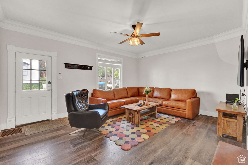 Living area with ornamental molding, wood finished floors, and baseboards