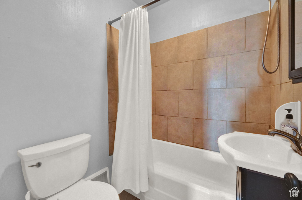 Bathroom with shower / tub combo with curtain, vanity, and toilet