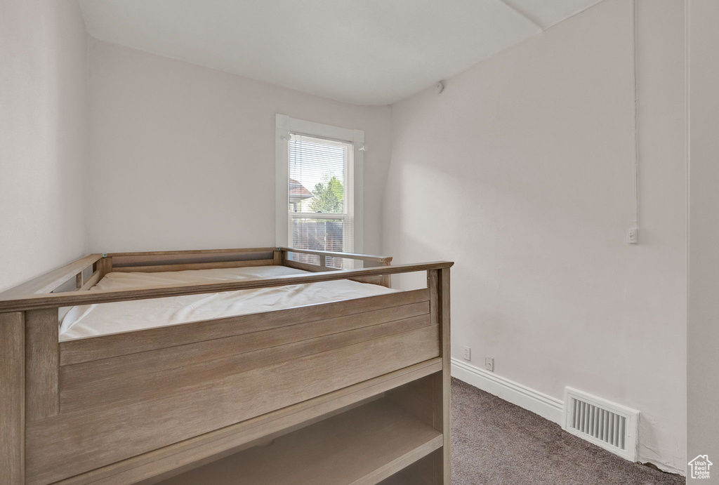 Unfurnished bedroom with carpet floors, visible vents, and baseboards