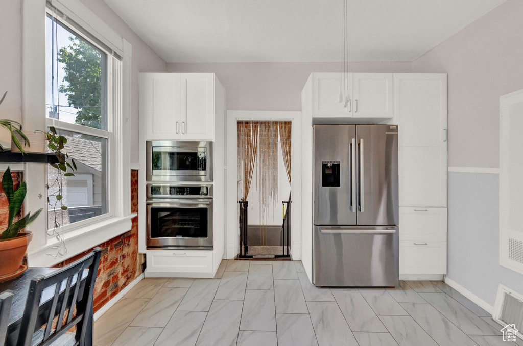 Kitchen featuring baseboards, appliances with stainless steel finishes, visible vents, and white cabinets