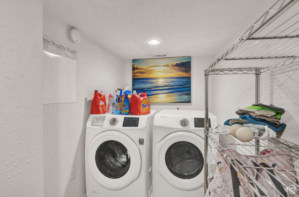 Clothes washing area featuring laundry area, visible vents, a textured wall, independent washer and dryer, and a textured ceiling