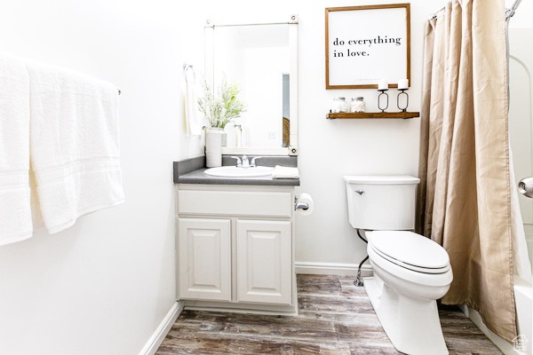 Bathroom with toilet, baseboards, wood finished floors, and vanity