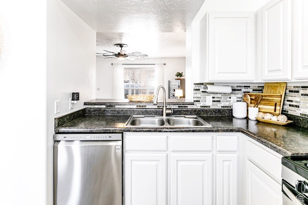 Kitchen with a sink, a ceiling fan, appliances with stainless steel finishes, backsplash, and dark countertops