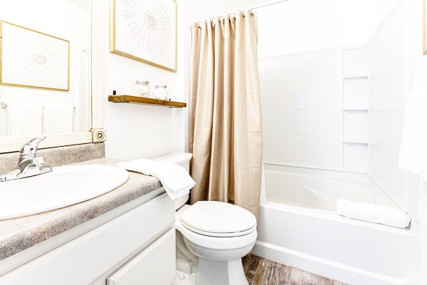 Bathroom with shower / tub combo, vanity, toilet, and wood finished floors