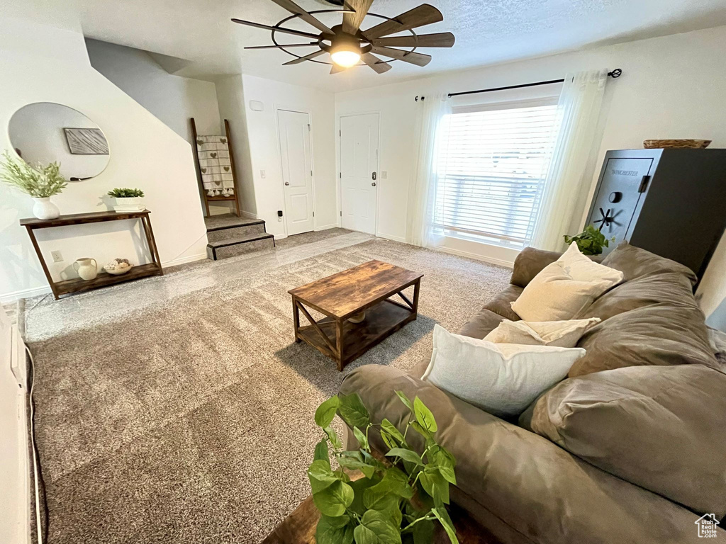 Living room with stairs, a textured ceiling, baseboards, and a ceiling fan