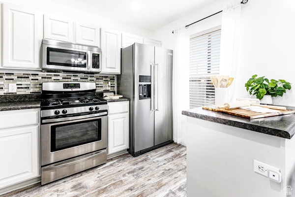 Kitchen featuring stainless steel appliances, dark countertops, and white cabinetry