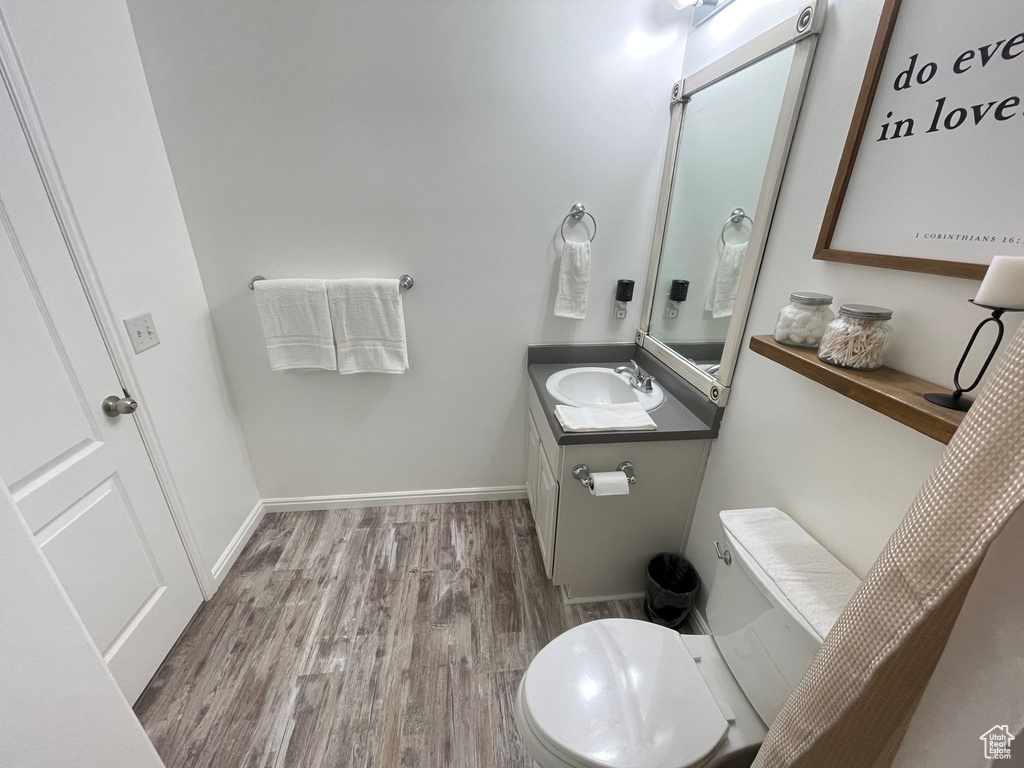 Bathroom with toilet, wood finished floors, vanity, and baseboards