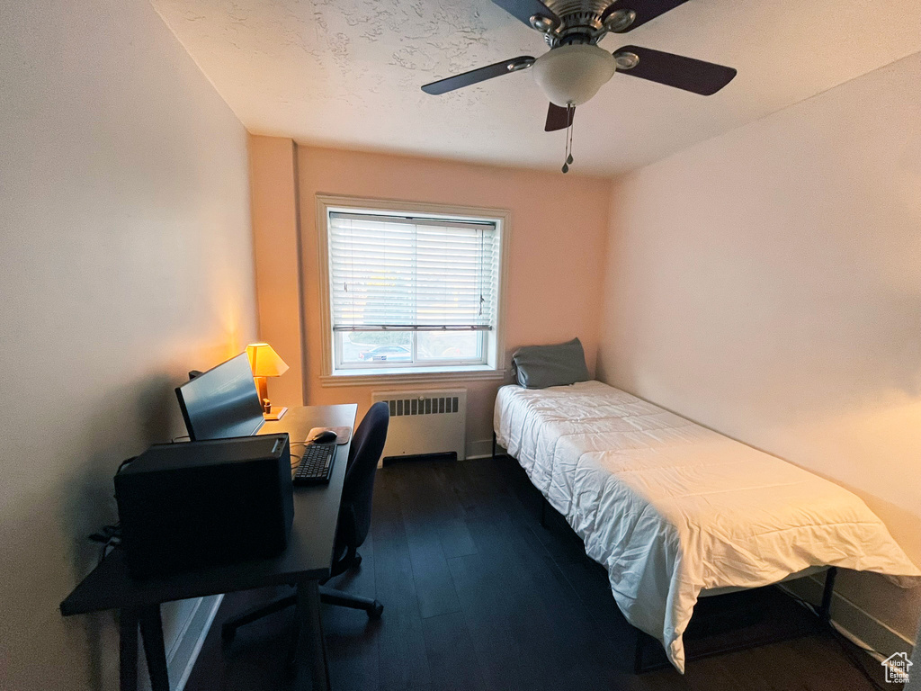 Bedroom featuring radiator, dark wood-style flooring, a desk, and a ceiling fan