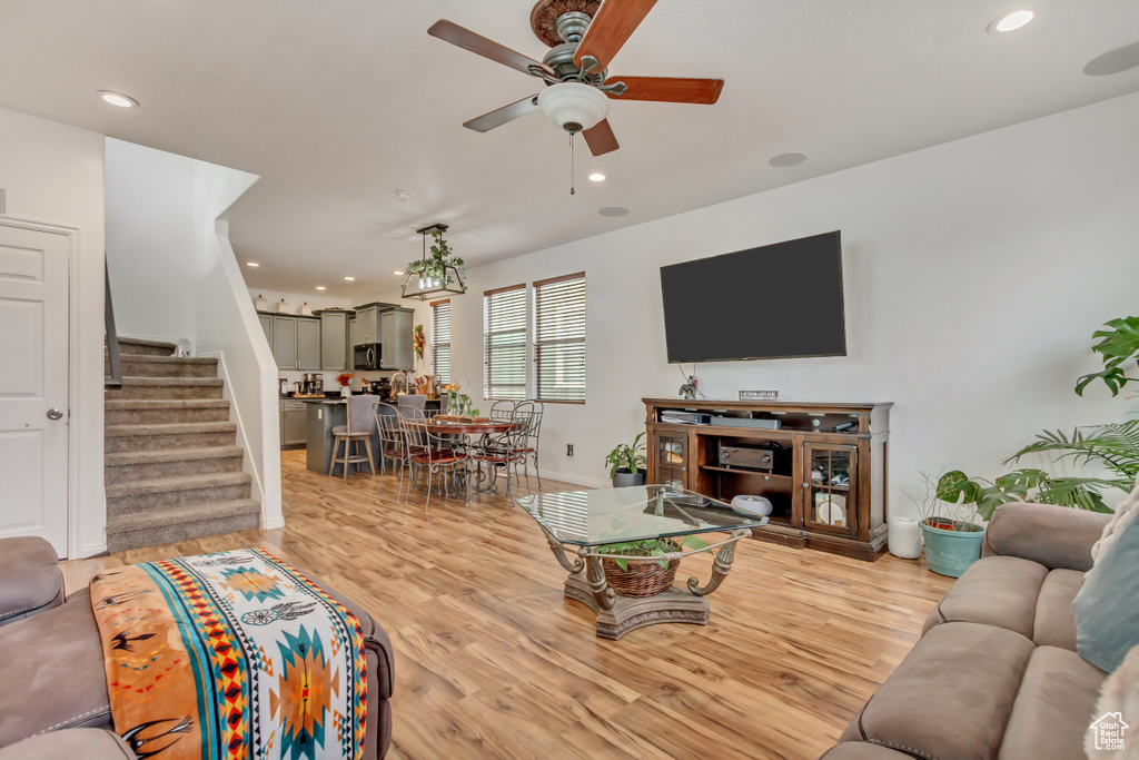 Living area with light wood-style flooring, stairs, ceiling fan, and recessed lighting