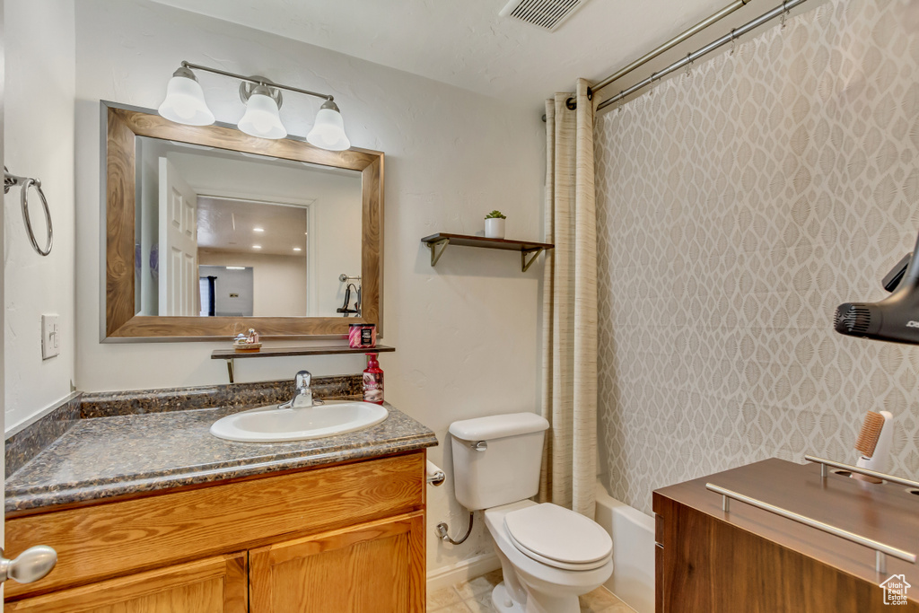 Full bathroom featuring visible vents, toilet, shower / bath combo, vanity, and tile patterned flooring