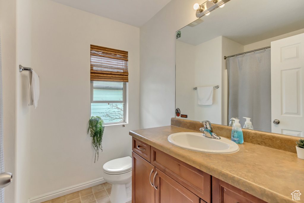 Full bathroom featuring toilet, tile patterned floors, vanity, baseboards, and a shower with curtain