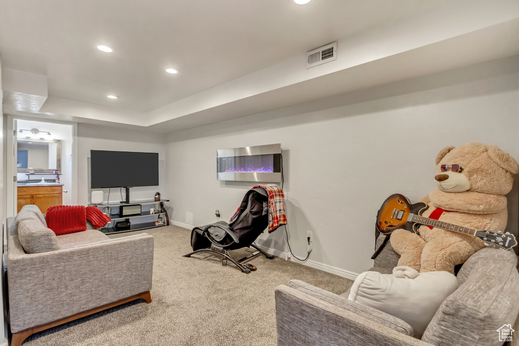 Carpeted living room featuring recessed lighting, a tray ceiling, visible vents, and baseboards