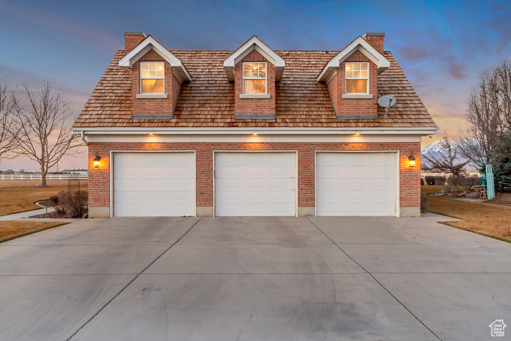 View of front facade featuring a garage, brick siding, and a chimney