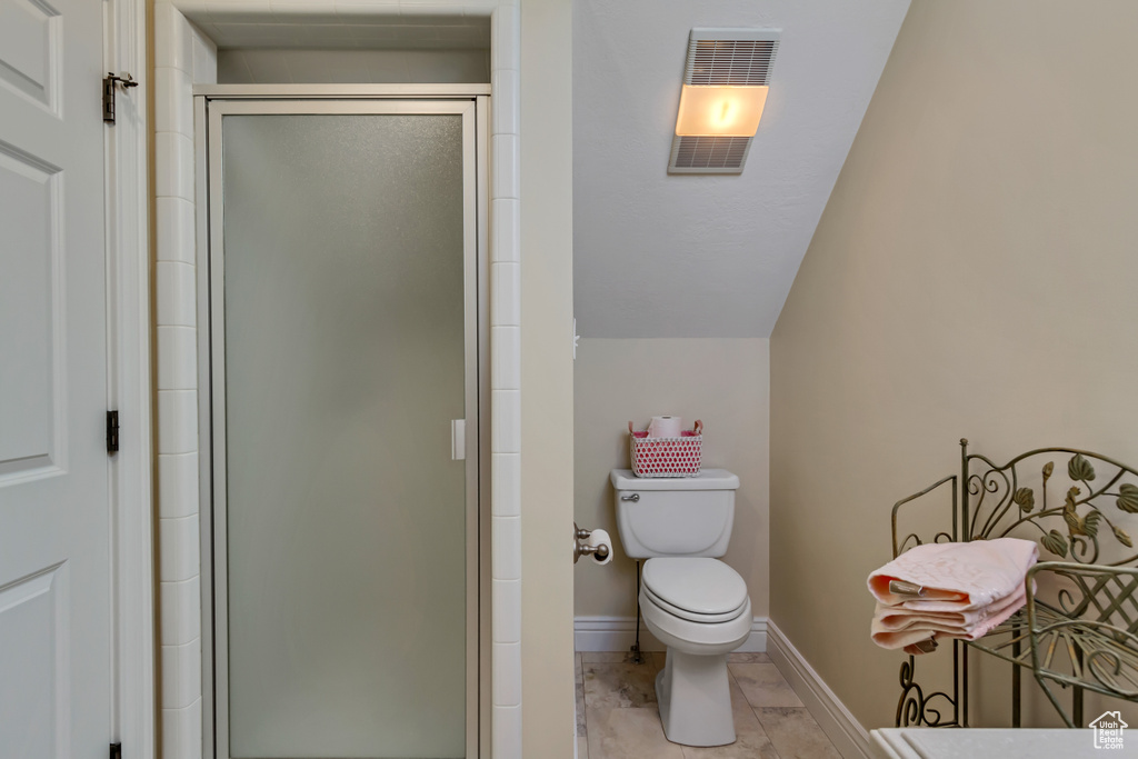 Bathroom featuring toilet, visible vents, baseboards, vaulted ceiling, and a stall shower