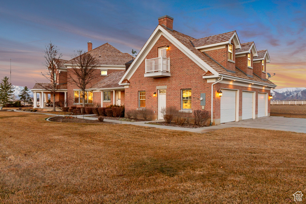 View of front facade with a balcony, a front yard, concrete driveway, and brick siding