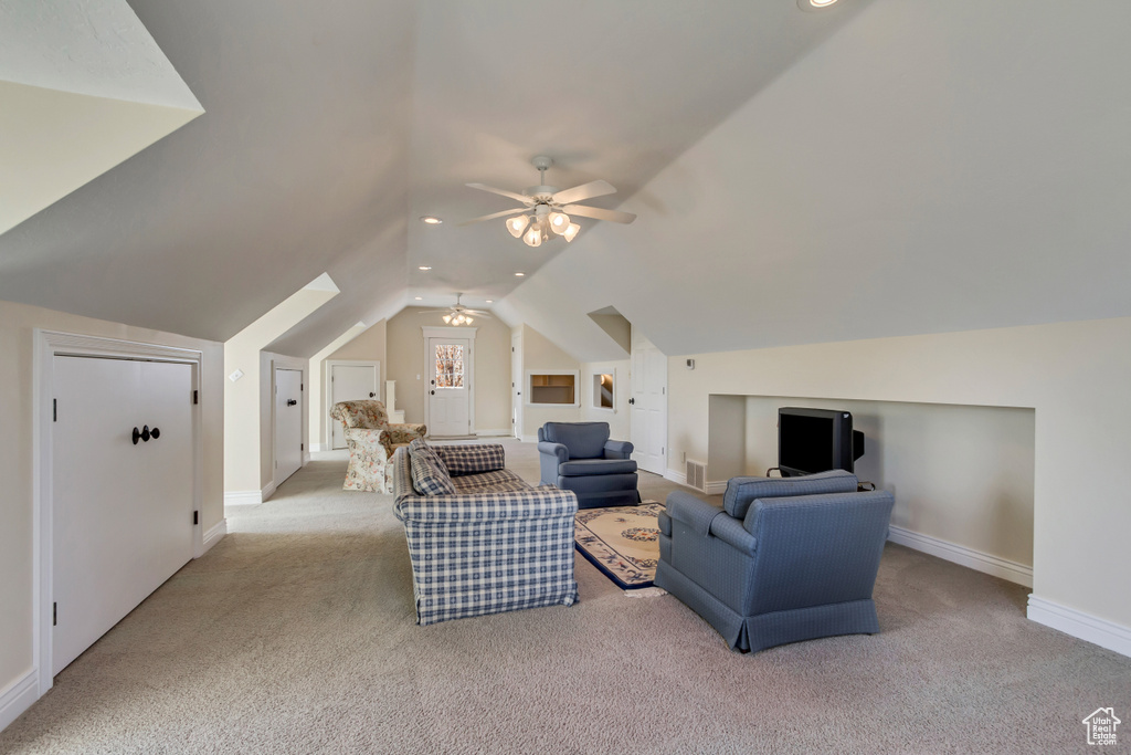 Living area with visible vents, baseboards, ceiling fan, carpet, and vaulted ceiling