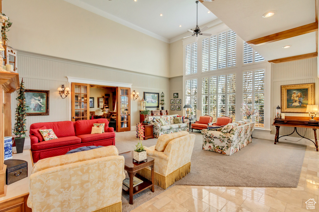 Living area featuring crown molding, a high ceiling, and ceiling fan