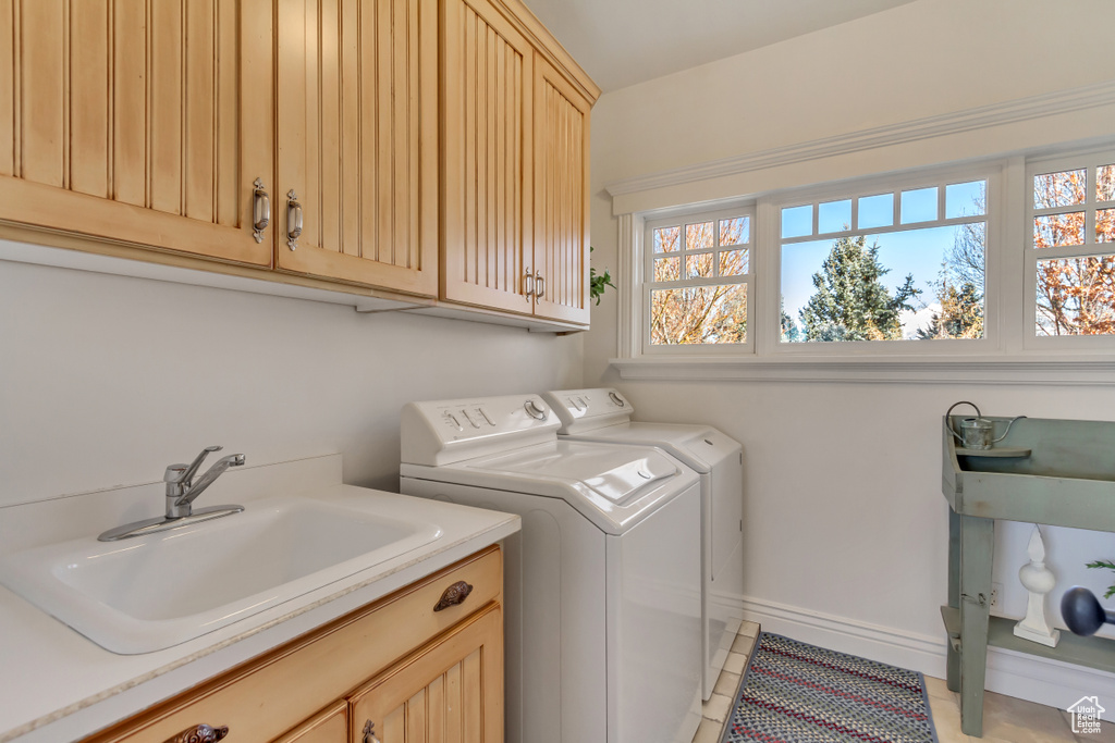 Laundry room with cabinet space, baseboards, washing machine and dryer, a sink, and light tile patterned flooring