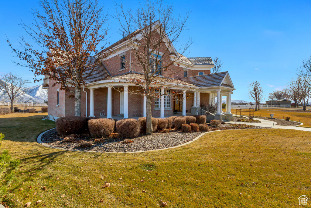 Exterior space with brick siding, a lawn, a porch, and fence