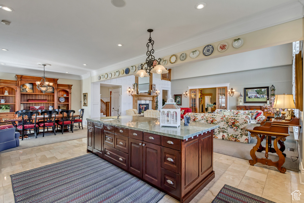 Kitchen with a chandelier, open floor plan, light stone counters, and decorative light fixtures