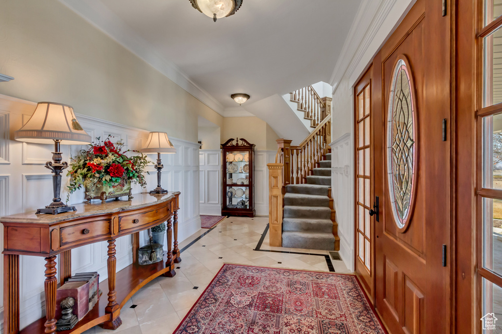 Entrance foyer featuring wainscoting, stairs, crown molding, french doors, and a decorative wall