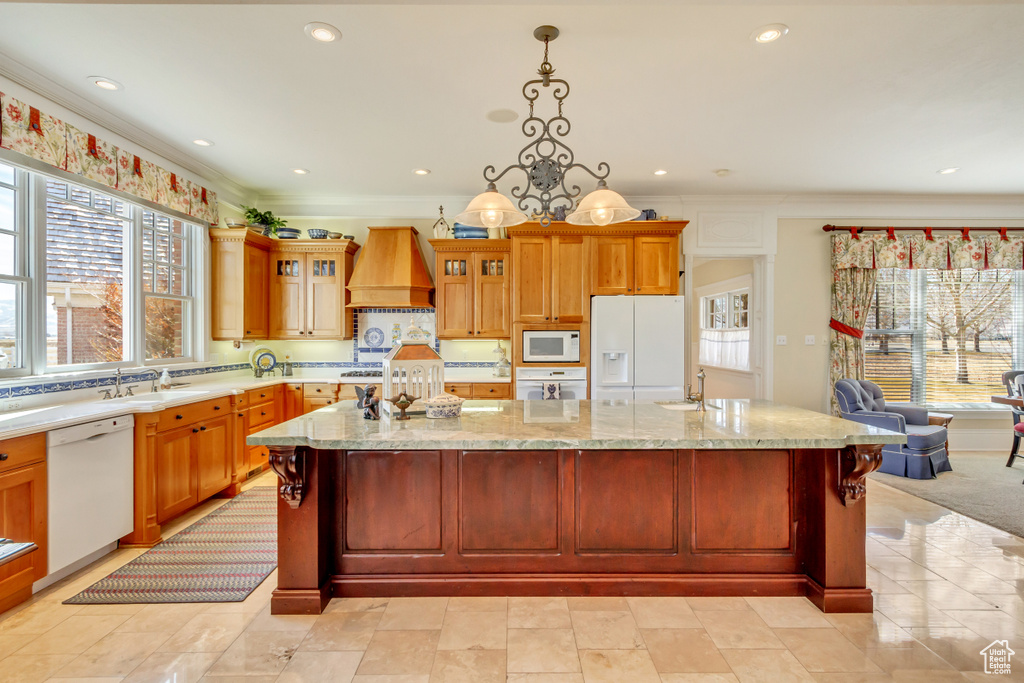 Kitchen featuring premium range hood, white appliances, a sink, a large island, and glass insert cabinets