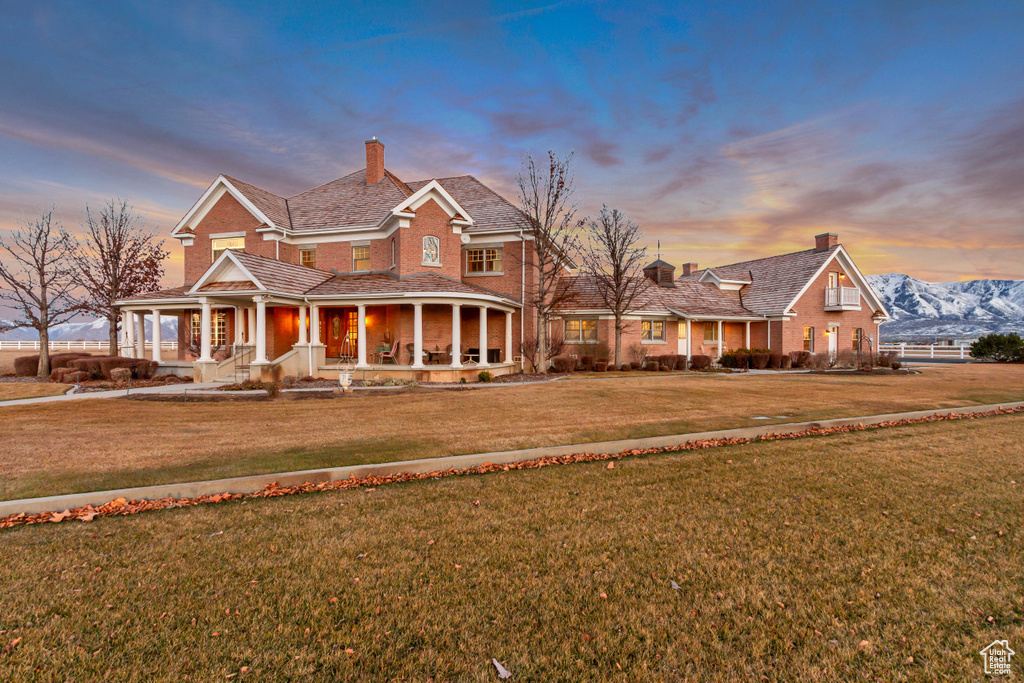 View of front of house with a front lawn, a chimney, a porch, and brick siding