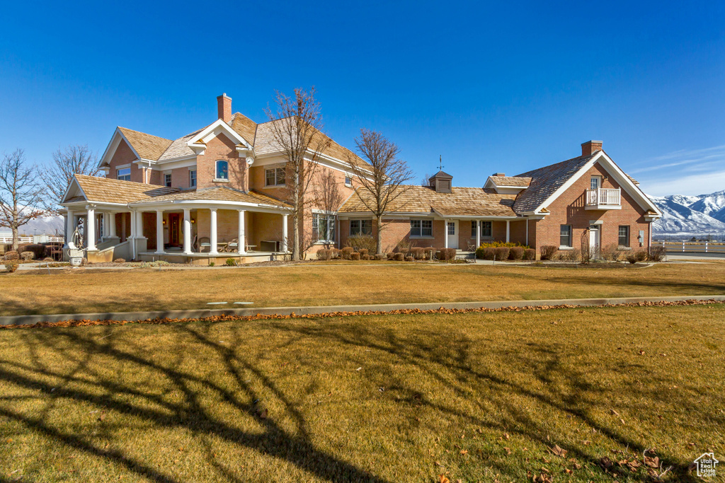 View of front of property with a porch, a chimney, and a front lawn