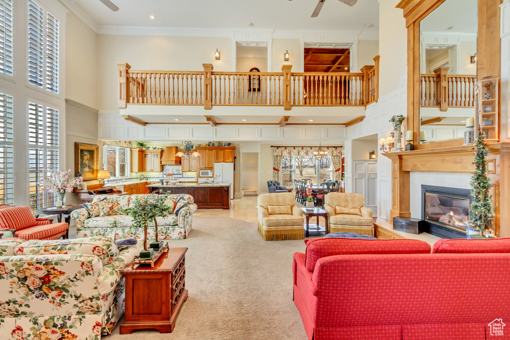 Living room featuring ornamental molding, light carpet, a high ceiling, and a ceiling fan