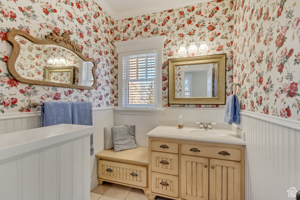 Bathroom with tile patterned flooring, wainscoting, crown molding, and wallpapered walls