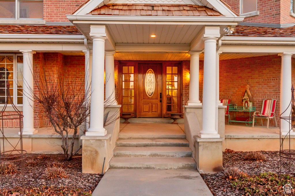 Property entrance featuring covered porch and brick siding