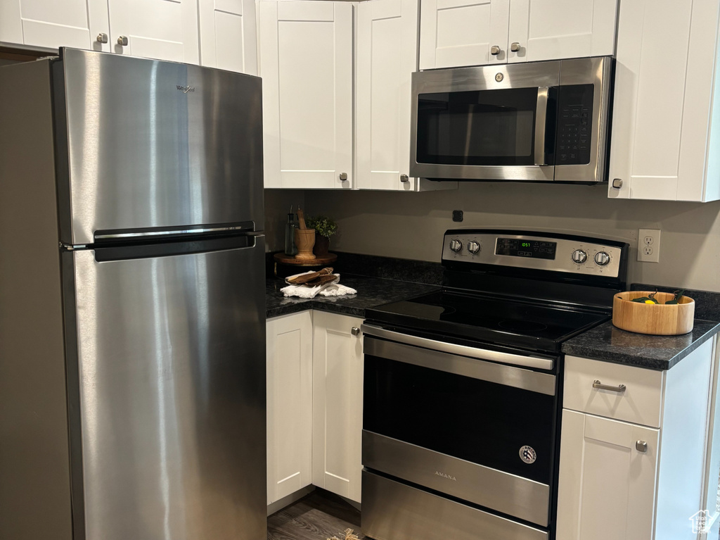 Kitchen featuring stainless steel appliances, dark wood-style flooring, white cabinets, and recessed lighting