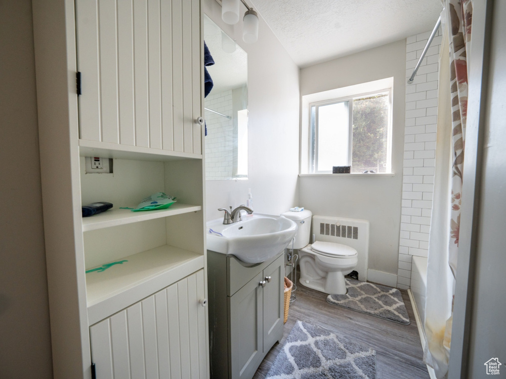Bathroom featuring toilet, radiator heating unit, a textured ceiling, vanity, and wood finished floors