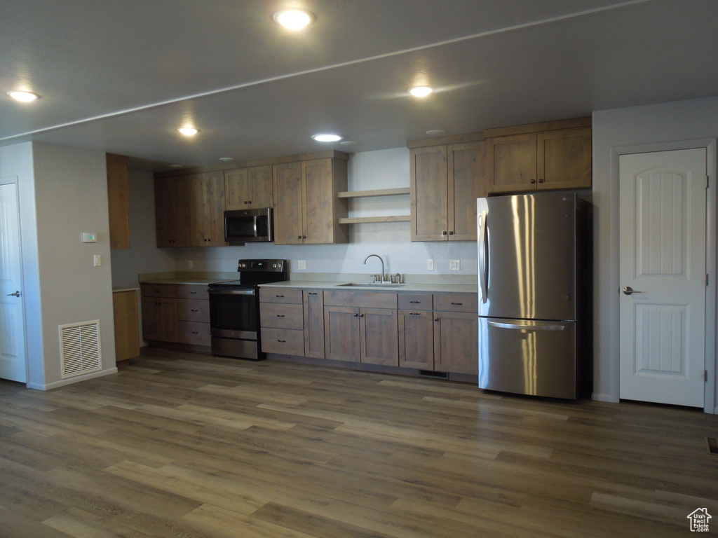 Kitchen featuring stainless steel appliances, dark wood-type flooring, a sink, visible vents, and open shelves