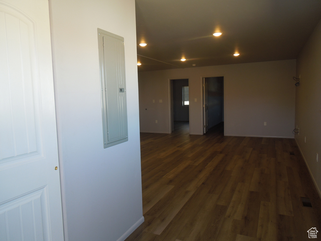 Empty room with recessed lighting, dark wood-type flooring, visible vents, baseboards, and electric panel