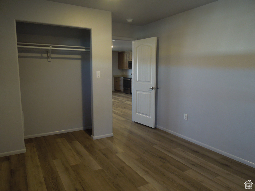 Unfurnished bedroom with a closet, wood finished floors, and baseboards