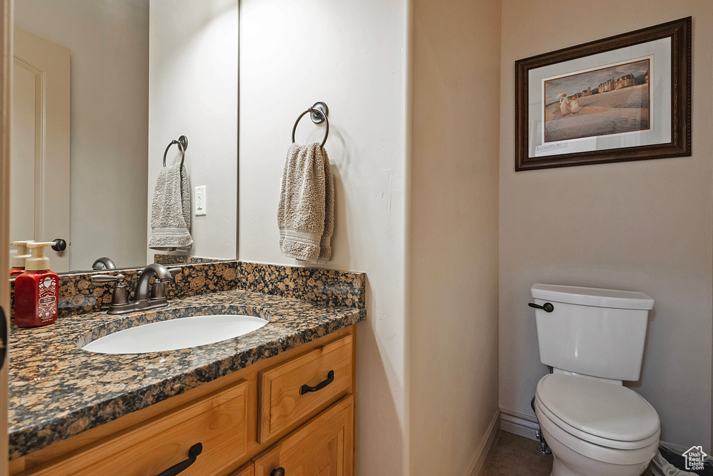 Half bathroom featuring toilet, baseboards, and vanity