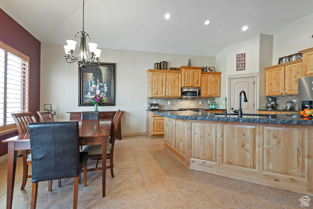 Kitchen with vaulted ceiling, stainless steel microwave, hanging light fixtures, and a sink