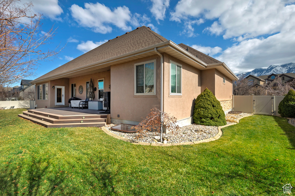 Back of property with a yard, stucco siding, a gate, a deck, and a fenced backyard