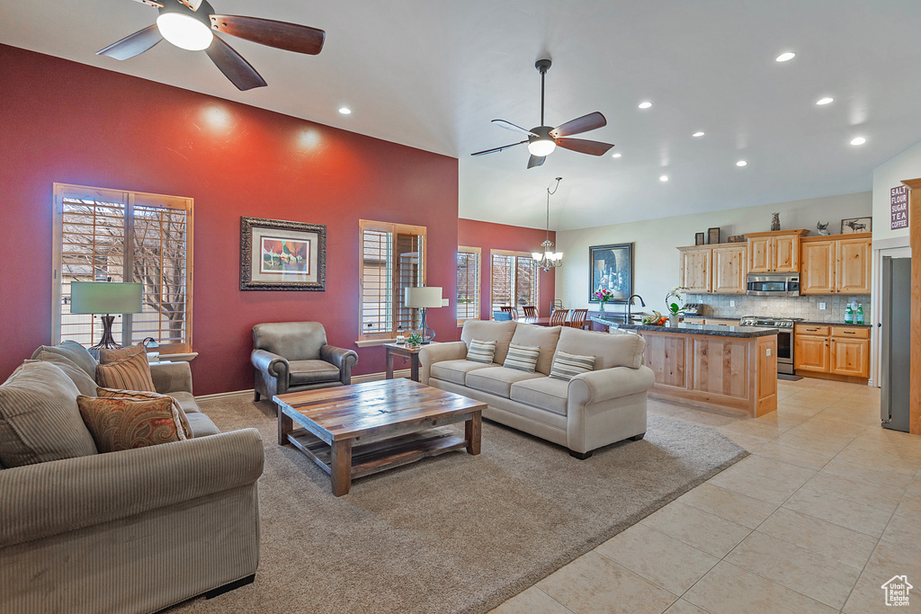 Living area with high vaulted ceiling, recessed lighting, light tile patterned floors, and ceiling fan with notable chandelier