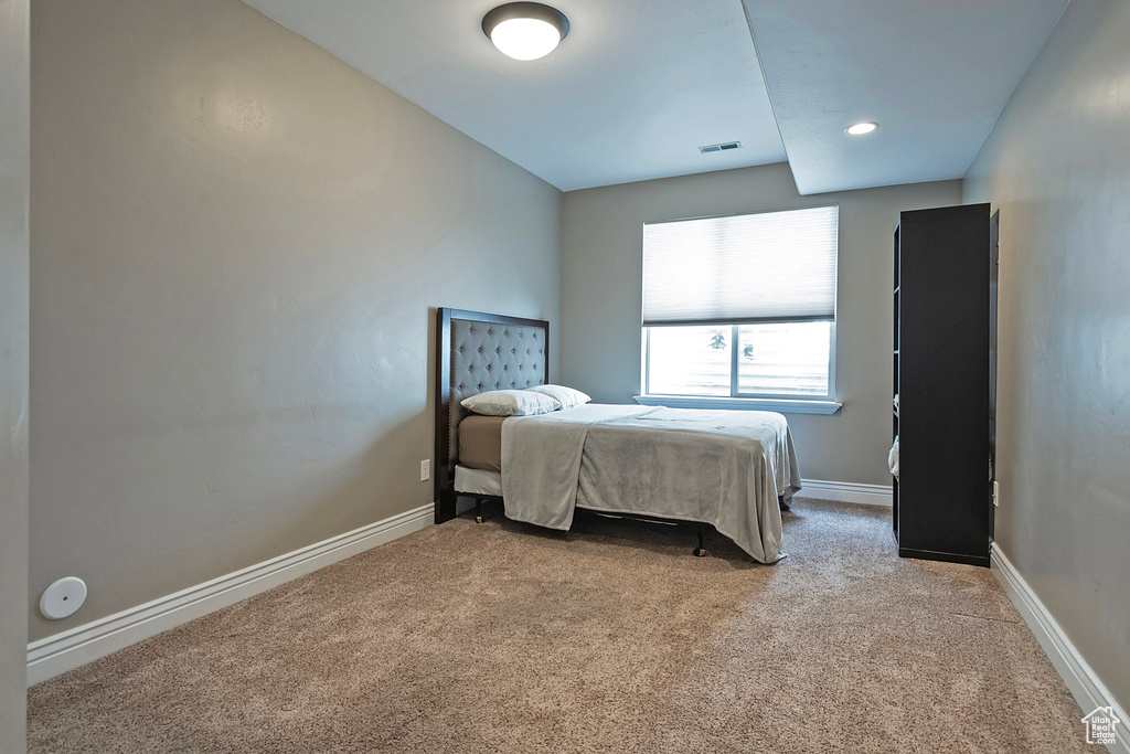 Bedroom with light colored carpet, visible vents, and baseboards