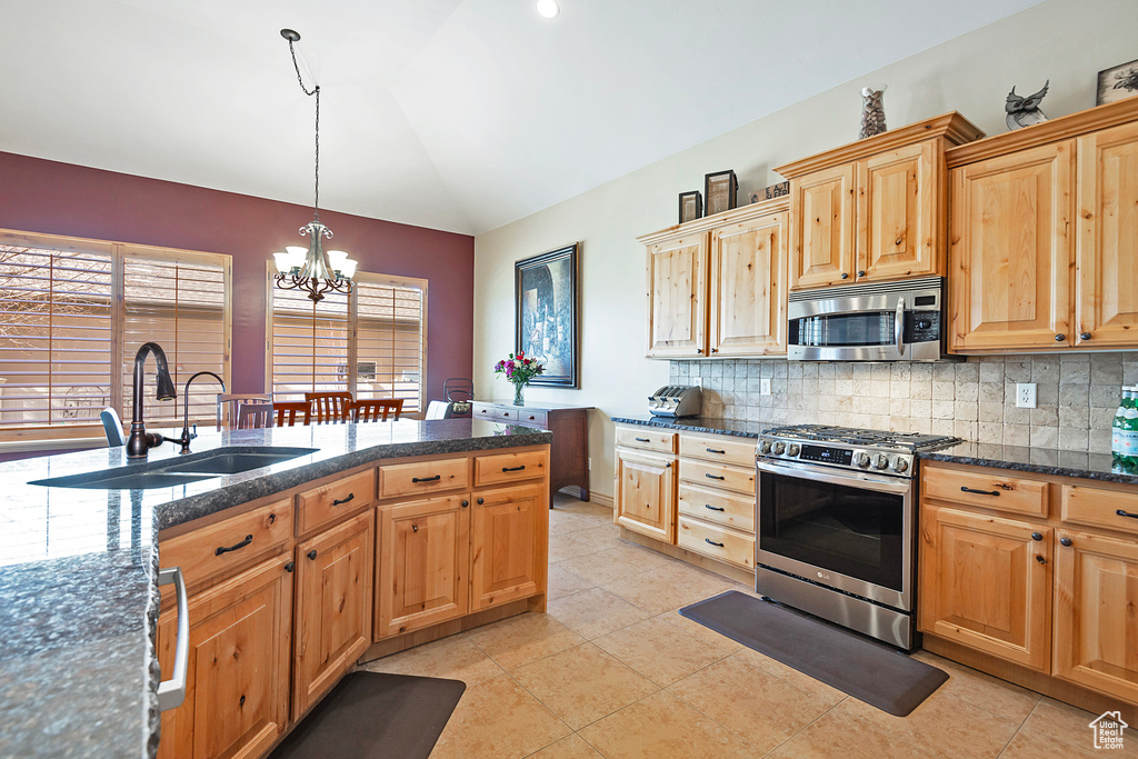 Kitchen featuring pendant lighting, stainless steel appliances, lofted ceiling, tasteful backsplash, and a sink