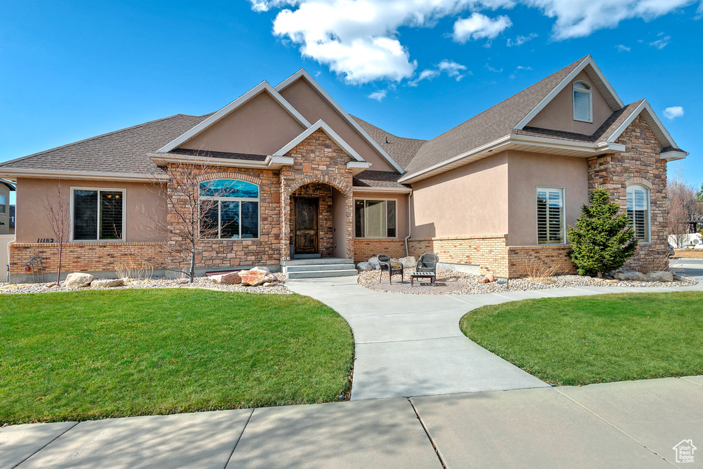 Craftsman-style house with a fire pit, a front lawn, and stucco siding