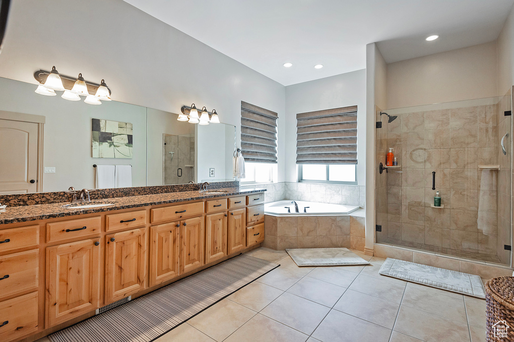 Bathroom with double vanity, a stall shower, a garden tub, tile patterned flooring, and a sink