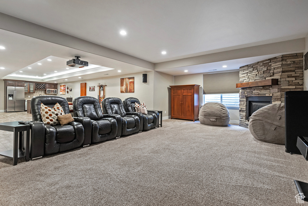 Home theater featuring a fireplace, recessed lighting, a raised ceiling, light colored carpet, and baseboards