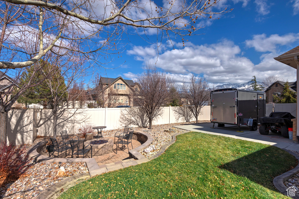 View of yard with an outbuilding, a patio, a storage shed, a fenced backyard, and a fire pit